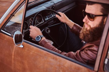 Sakallı erkek güneş gözlüğü retro bir araba kahverengi deri ceket giymiş.