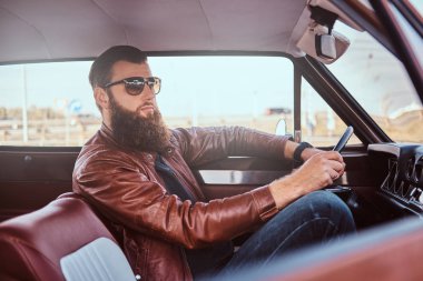 Sakallı erkek güneş gözlüğü retro bir araba kahverengi deri ceket giymiş.