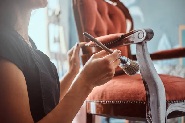 Künstlerin bemalt Vintage Stuhl in weißer Farbe mit Pinsel in der Werkstatt. — Stockfoto