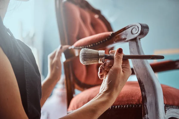 Artista feminina pintando cadeira vintage na cor branca com pincel na oficina . — Fotografia de Stock