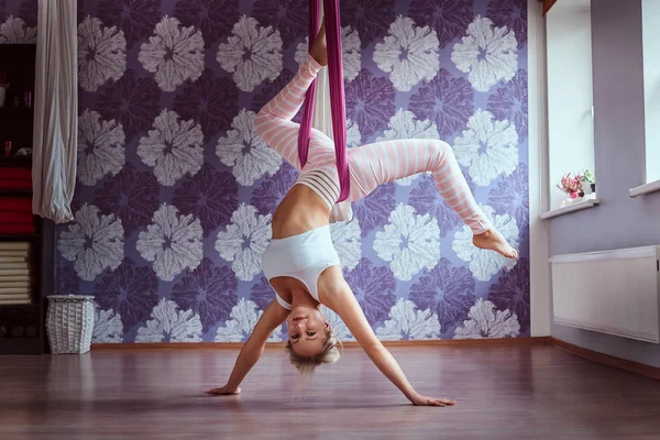 Wanita muda melakukan latihan yoga udara di hammock ungu di klub kebugaran . — Stok Foto