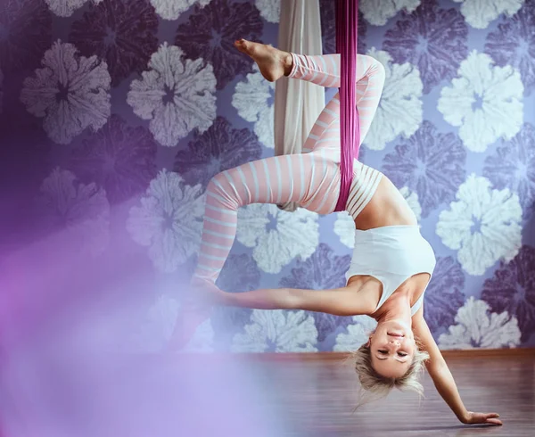 Mujer joven practicando yoga aéreo en hamaca púrpura en club de fitness . —  Fotos de Stock