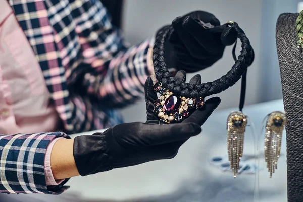 Close-up photo of a jewelry worker presenting a costly necklace with gemstones in a jewelry store. — Stock Photo, Image