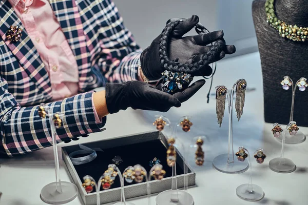 Nahaufnahme eines Schmuckarbeiters, der in einem Juweliergeschäft eine kostspielige Halskette mit Edelsteinen präsentiert. — Stockfoto