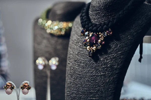 Colliers avec pierres précieuses sur un buste de bijoux noirs dans un magasin . — Photo