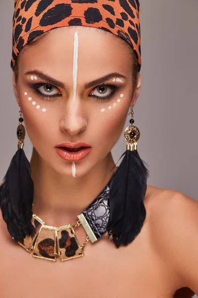 Schöne kaukasische Frau mit Make-up und buntem Schal auf dem Kopf und Accessoires. isoliert auf grauem Hintergrund. — Stockfoto