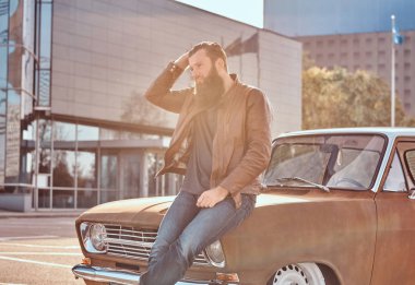 Şık erkek üzerine eğilerek parlak gün batımında gökdelen Park City retro araba ayarlı.