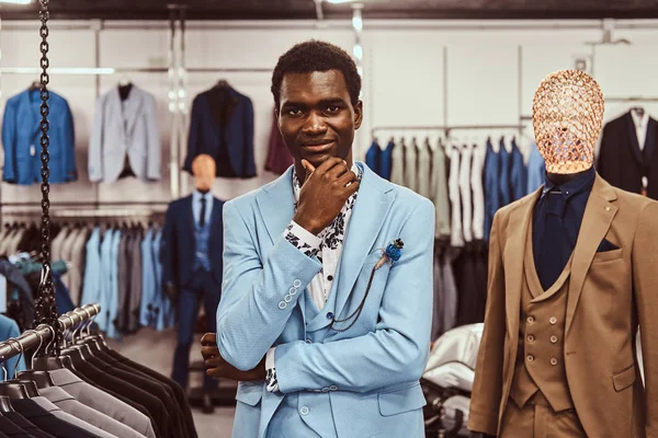 穿着优雅的非洲男子摆着手在下巴, 而站在一个经典的男装店. — 图库照片