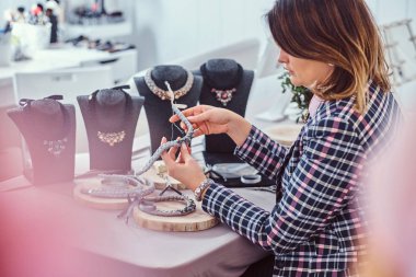 İğne ve iplik atölyesinde çalışan el yapımı kolye, zarif giyimli kadın yapar.