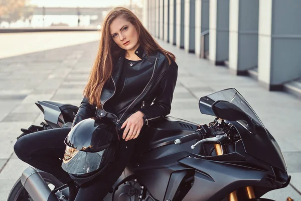 Ein sexy Bikermädchen posiert auf ihrem Superbike vor einem Gebäude. — Stockfoto