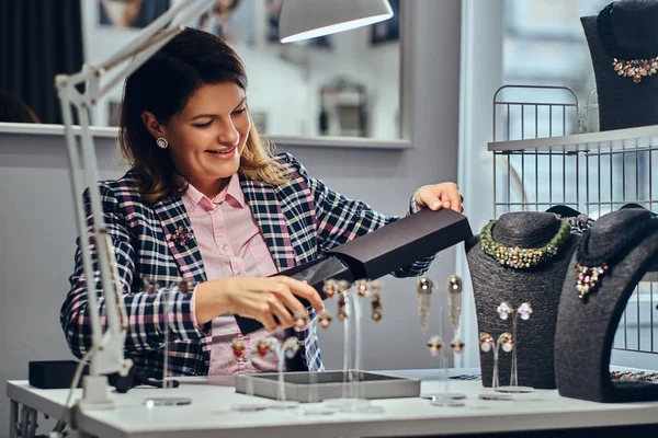 Elegantemente vestido mujer vendedor paquetes collar en una caja para su cliente en una joyería de lujo . — Foto de Stock