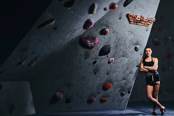 Ajuste chica estudiante deportiva en pantalones cortos y sujetador deportivo apoyado en la pared de bouldering en el gimnasio . — Foto de Stock