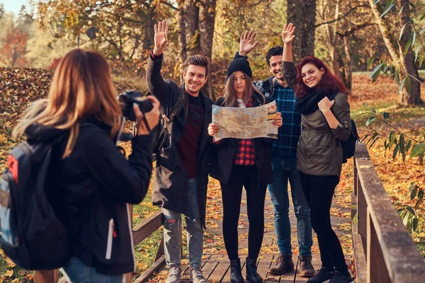 Chica tomando una foto de sus amigos. Grupo de jóvenes amigos caminando por el bosque . — Foto de Stock