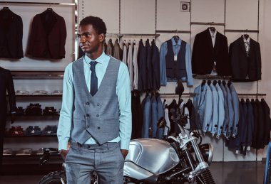 Zarif Afrikalı-Amerikalı genç giyinmiş retro poz erkek spor erkek giyim mağazası, motosiklet.