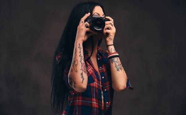 Getatoeëerd meisje nemen van een foto kijken camera in een studio. — Stockfoto