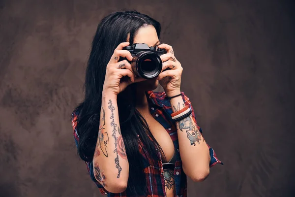 Tetovaný dívka fotografování při pohledu na fotoaparát ve studiu. — Stock fotografie