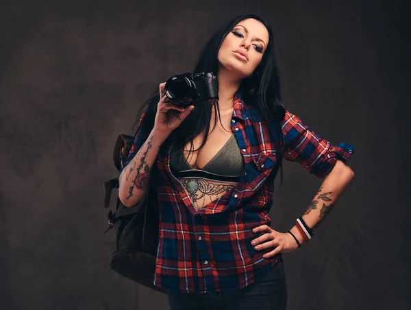 Chica hipster tatuada seductora con una camisa a cuadros desabotonada roja posando una cámara . — Foto de Stock