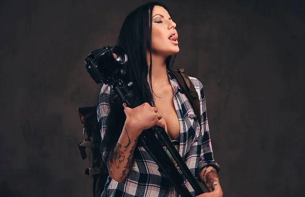 Seductive tattooed girl wearing an unbuttoned checked shirt girl posing with a camera. — Stock Photo, Image