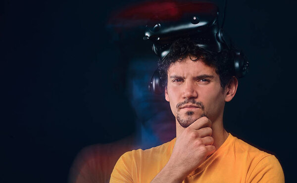 Portrait of a pensive male with bristle in yellow shirt wearing virtual reality goggles.
