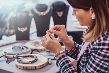 İğne ve iplik atölyesinde çalışan el yapımı kolye, zarif giyimli kadın yapar.