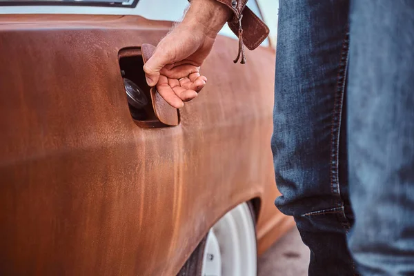 Manlig hand öppnar gas locket på en trimmad retro bil för tankning. — Stockfoto