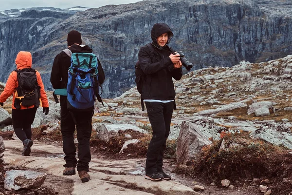 Il fotografo turista con la macchina fotografica si è fermato per fare uno scatto. Gruppo di turisti in gita sulle montagne della Norvegia . — Foto Stock