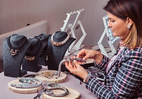 Elegantly dressed woman makes handmade necklaces in jewelry workshop. — Stock Photo, Image