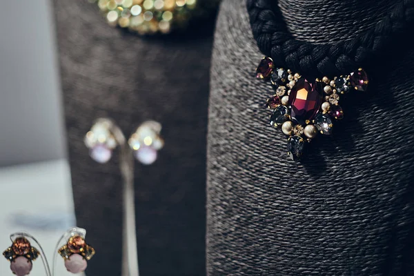 Necklaces with gemstones on a black jewelry bust in a store. — Stock Photo, Image