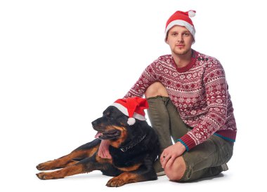 Onun köpek ile oturup Noel Baba şapkası giyen genç bir adam.