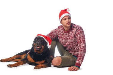 Onun köpek ile oturup Noel Baba şapkası giyen genç bir adam.