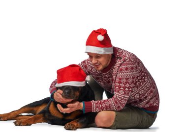 Onun köpek ile oturup Noel Baba şapkası giyen genç bir adam.