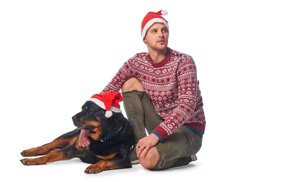 若い男が彼の純血種の犬と座っているサンタ帽子をかぶって. — ストック写真