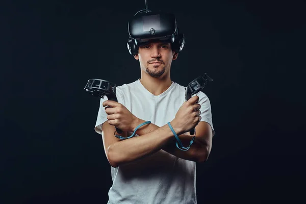 Pro gamer a sörte öltözött fehér inget, virtuális valóság szemüveg, és birtokolja a joystick, keresztezett karokkal pózol. — Stock Fotó