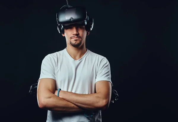 Pro gamer con cerdas vestidas con camisa blanca con gafas de realidad virtual y sostiene joysticks, posando con los brazos cruzados . —  Fotos de Stock