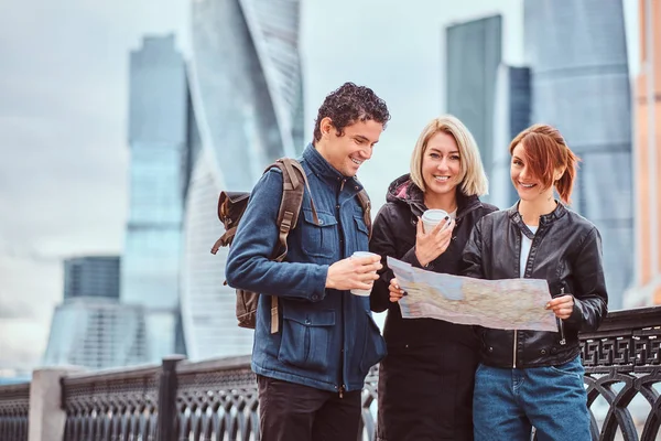 Groep tevreden toeristen zoeken op de kaart voor wolkenkrabbers — Stockfoto