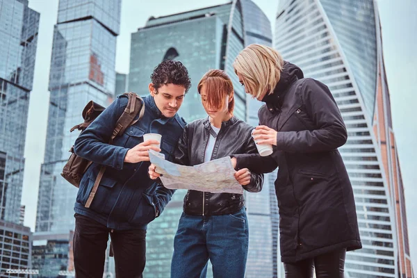 Group of tourists searching place on the map in front of skyscrapers