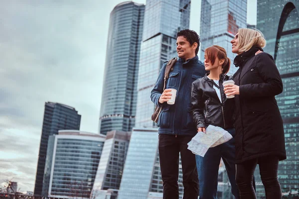 Группа туристов с картой и кофе на вынос перед небоскребами — стоковое фото