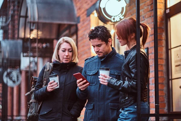 Tres amigos estudiantes tomando un descanso con café cerca de un café afuera . —  Fotos de Stock