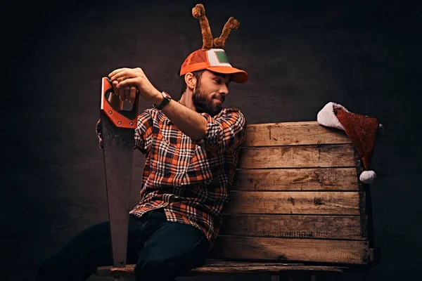 Tischler mit geschmückter Weihnachtsmütze sitzt auf einer Holzpalette. — Stockfoto