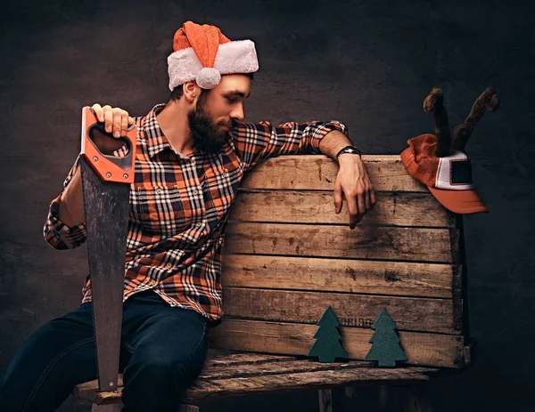 Tischler mit verzierter Weihnachtsmütze sitzt auf einer Holzpalette. — Stockfoto