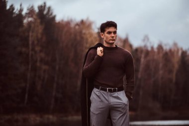 Kendine güvenen genç bir adam yakın bir göl sonbahar ormanda.