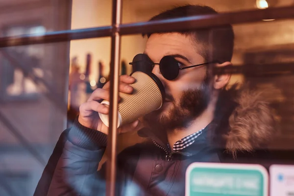 一个英俊的年轻时尚男子在窗后的咖啡馆里喝咖啡. — 图库照片