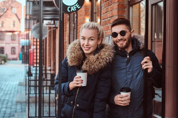 Sorrindo casal atraente vestindo casacos de inverno segurando um café takeaway — Fotografia de Stock
