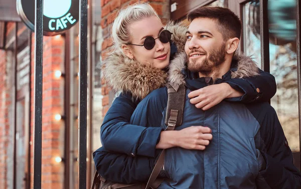 A happy attractive couple wearing winter coats is spending time together outdoors. — Stock Photo, Image