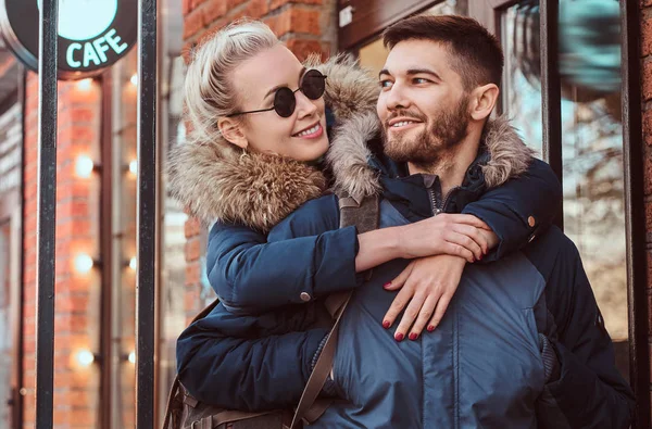 Um casal atraente feliz vestindo casacos de inverno está passando tempo juntos ao ar livre . — Fotografia de Stock