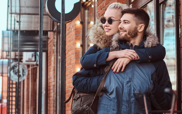 A happy attractive couple wearing winter coats is spending time together outdoors. — Stock Photo, Image