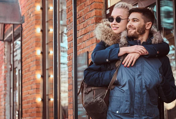 A happy attractive couple wearing winter coats is spending time together outdoors. — Stock Photo, Image