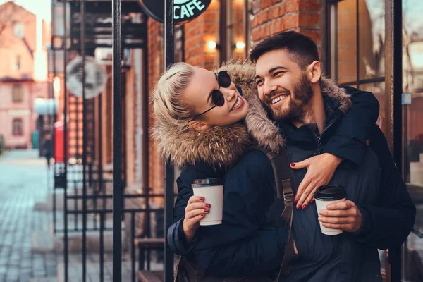 Una bella ragazza abbraccia il suo ragazzo vicino al caffè fuori . — Foto Stock