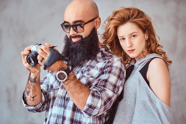 Retrato de un hombre árabe barbudo sosteniendo una cámara y su hermosa novia pelirroja . — Foto de Stock
