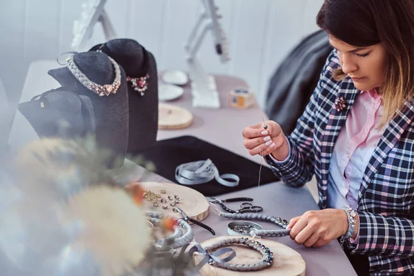 Mujer elegantemente vestida hace collares hechos a mano, trabajando con agujas e hilo en el taller . —  Fotos de Stock